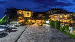 A hotel with a paved driveway, multiple parked cars, and well-lit buildings. - Atithi Resort & Spa (Pokhara)