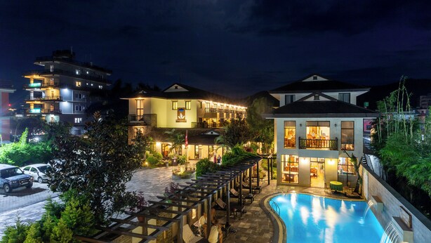 A hotel with a swimming pool, outdoor seating, and multiple balconies. - Atithi Resort & Spa (Pokhara)