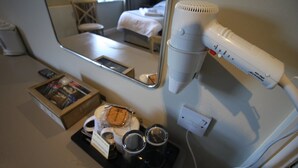 A hotel room with a bed, a hairdryer, a mirror, a tray with cups, and a magazine. - The Tawny Owl (Swindon)