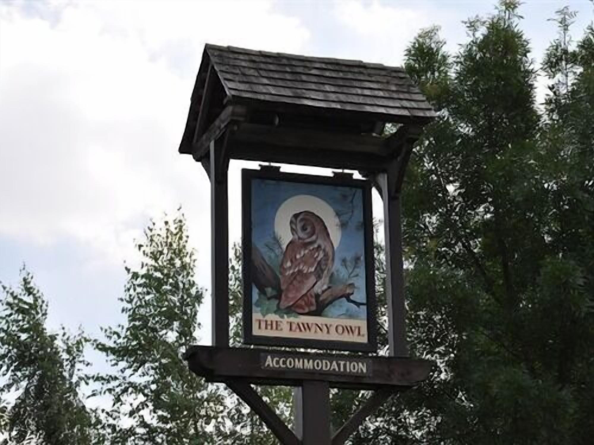 Une enseigne pour « The Tawny Owl Accommodation » représentant une chouette et une lune.