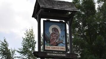 Une enseigne pour « The Tawny Owl Accommodation » représentant une chouette et une lune.