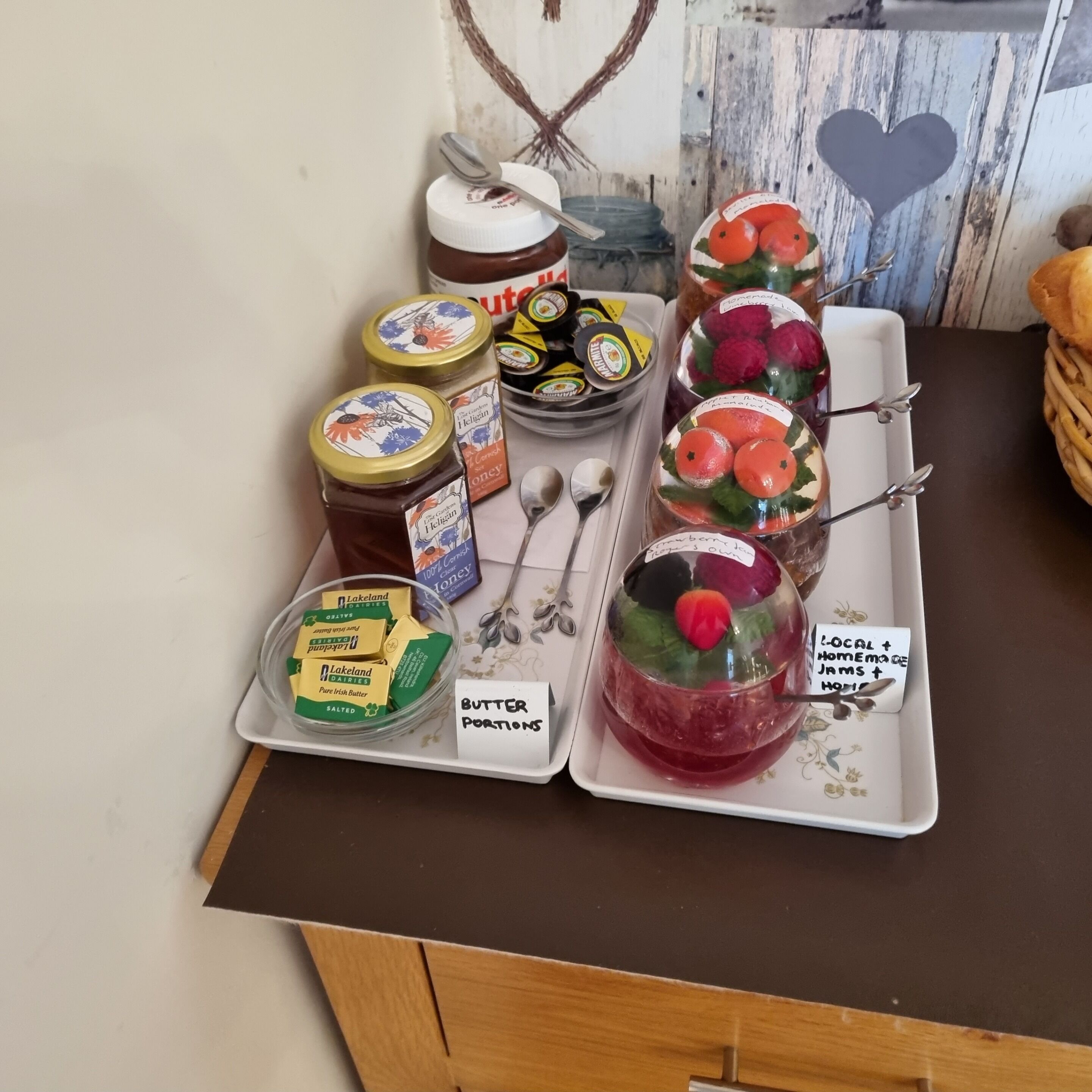 A tray with butter portions, jars of honey, and a glass with a fruit garnish.