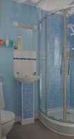 A bathroom with a glass-enclosed shower, a sink, and a mirror.