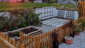 A garden area with a wooden fence, potted plants, and a raised garden bed. - Trevarrian Lodge (Newquay)