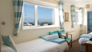 A bedroom with a bed, a chair, a desk, and a window with curtains. - Trevarrian Lodge (Newquay)