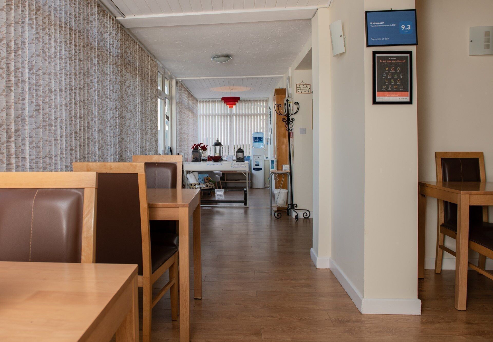 A hotel lobby with wooden furniture, a reception desk, and a framed award on the wall.