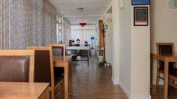 A hotel lobby with wooden furniture, a reception desk, and a framed award on the wall.