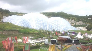 Una estructura grande y en forma de cúpula con un diseño hexagonal, rodeada por un área ajardinada con senderos y banderas.