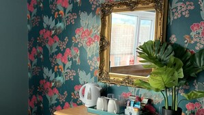 A wooden vanity with a mirror, a potted plant, and a tray with a kettle and glasses. - Waverley Bed & Breakfast (Minehead)