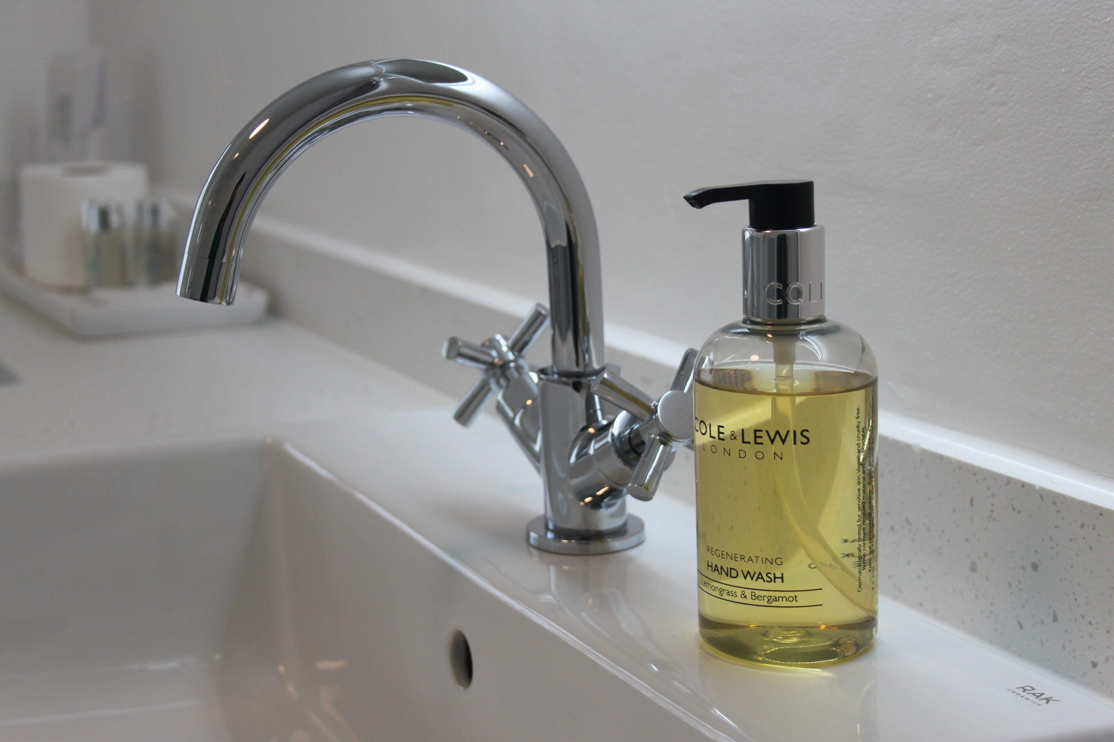 A bathroom sink with a chrome faucet and a bottle of hand wash soap.