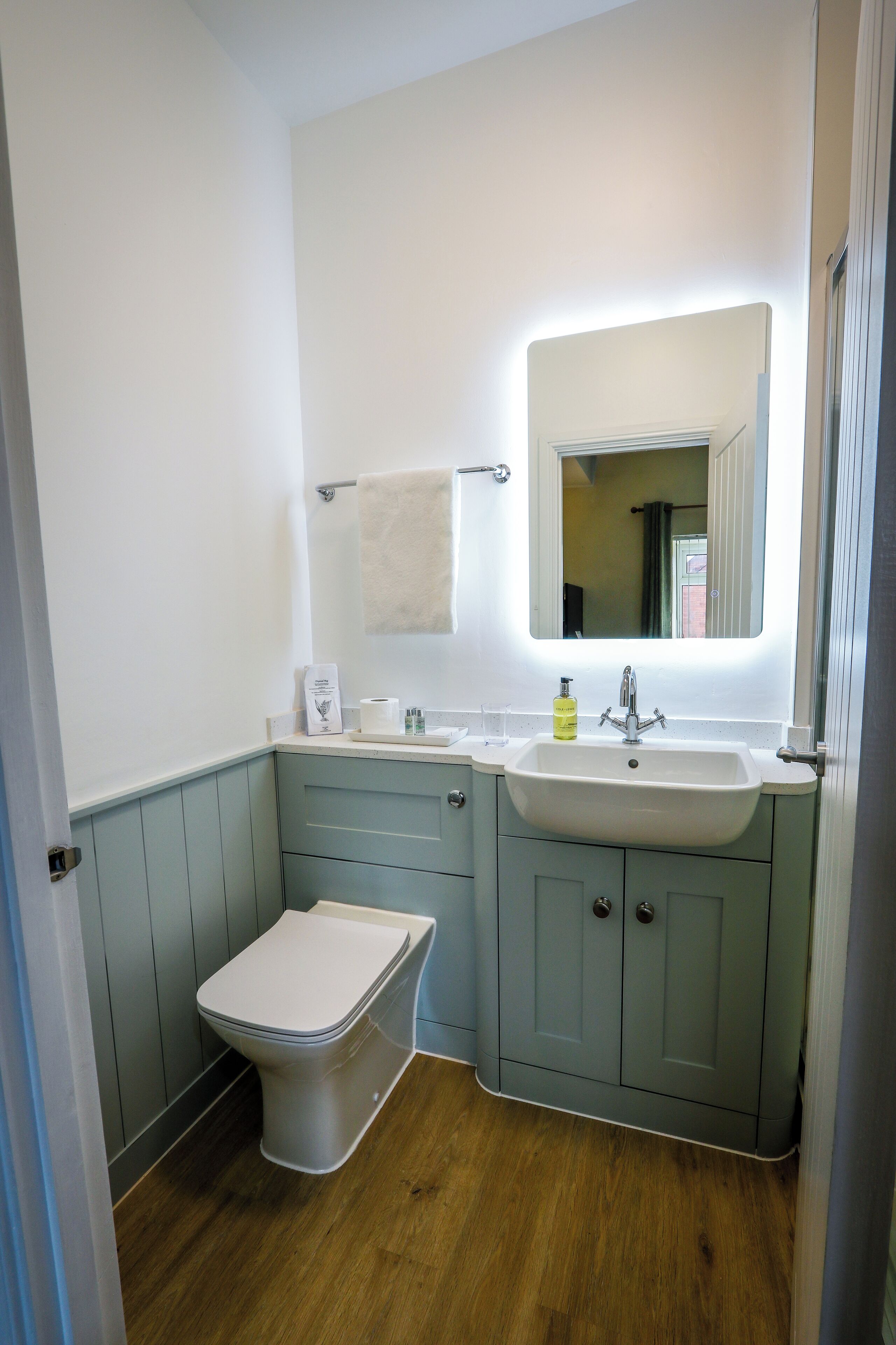 Un baño con lavamanos blanco, un espejo y un inodoro.