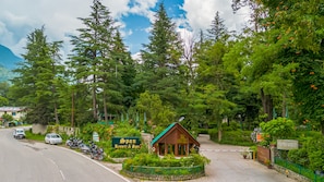 A resort entrance with a signboard, a small wooden building, and a paved pathway. - Span Resort & Spa, Manali - A Luxury Riverside Resort (Manali)