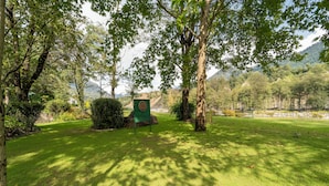 A park with a green sign, trees, and a bench.