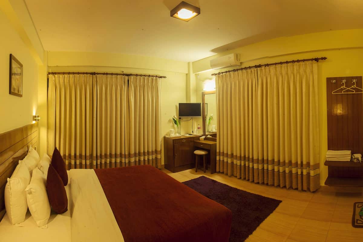 Une chambre d’hôtel comprenant un lit, un bureau avec une chaise, une télévision et une salle de bain avec un porte-serviettes.