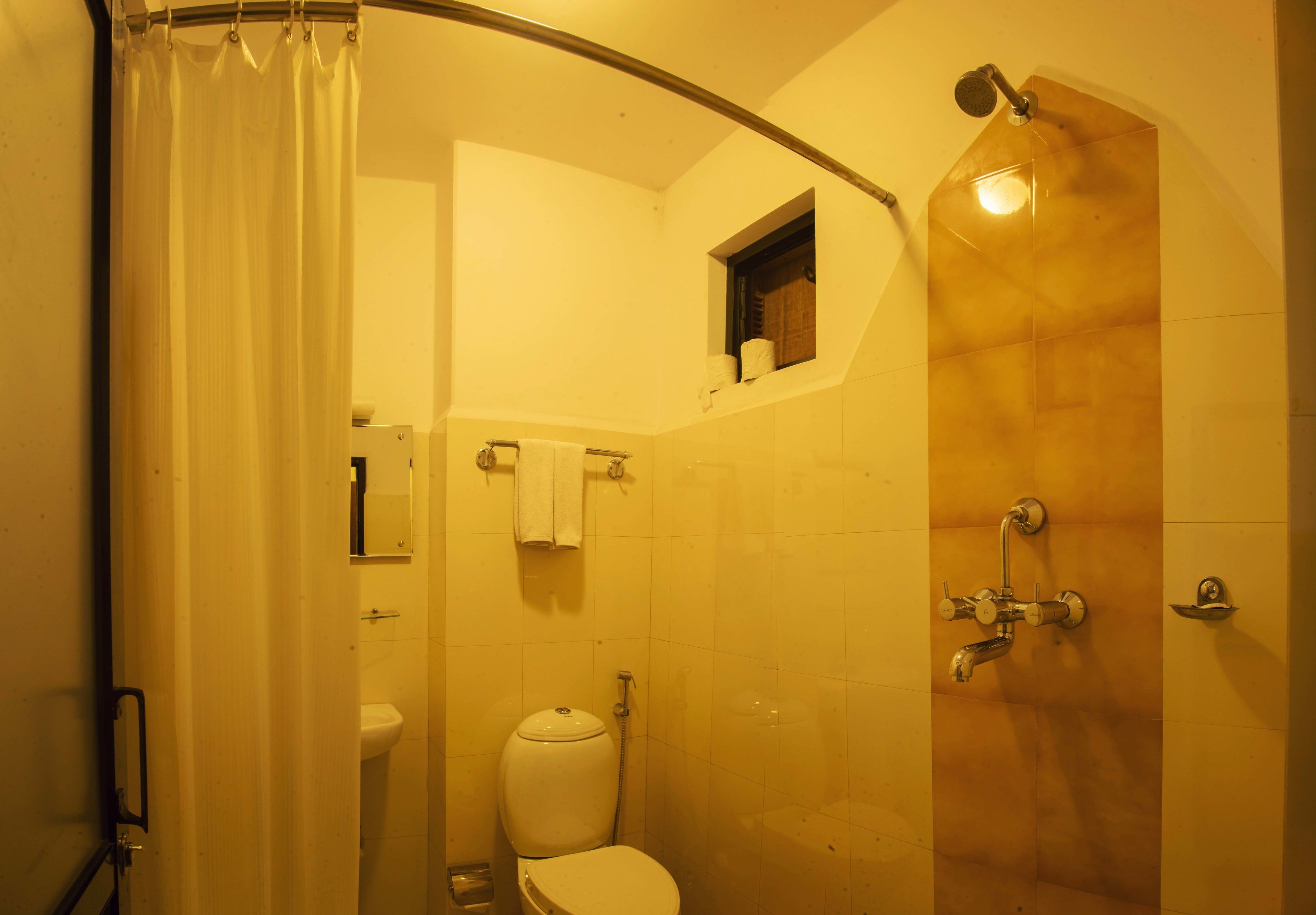 Un baño con ducha, inodoro y una pequeña ventana.