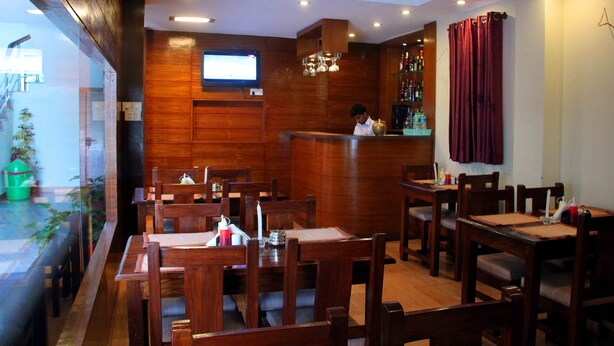 A restaurant with wooden walls, a bar area, and multiple dining tables and chairs. - Hotel Tara (Pokhara)