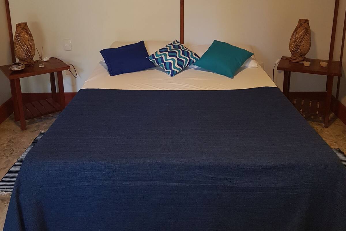 A bed with a blue bedspread, two pillows, and a wooden headboard with a map design.
