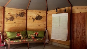 A wooden cabin interior with a wooden bench, a white curtain, and fish wall art. - Cabanas Paraíso (Angra dos Reis)