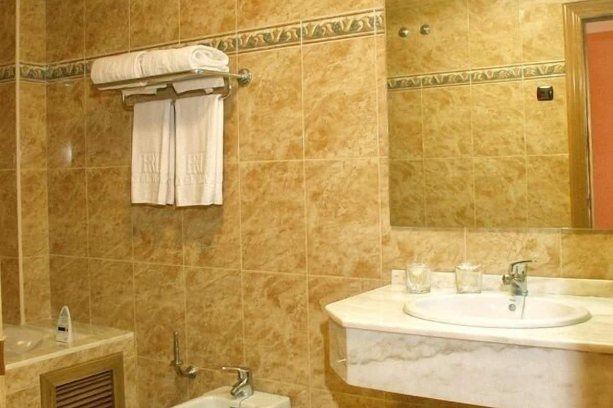 A bathroom with a bidet, a sink, and a mirror.
