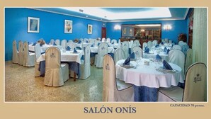 Un salón de banquetes con mesas redondas, sillas blancas y paredes azules.