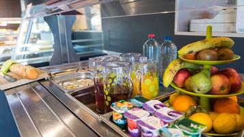 Een ontbijtbuffet met diverse soorten eten en drinken, zoals fruit, sapjes en yoghurt desserts.