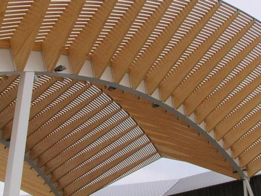 A wooden structure with a curved roof and a series of vertical slats.