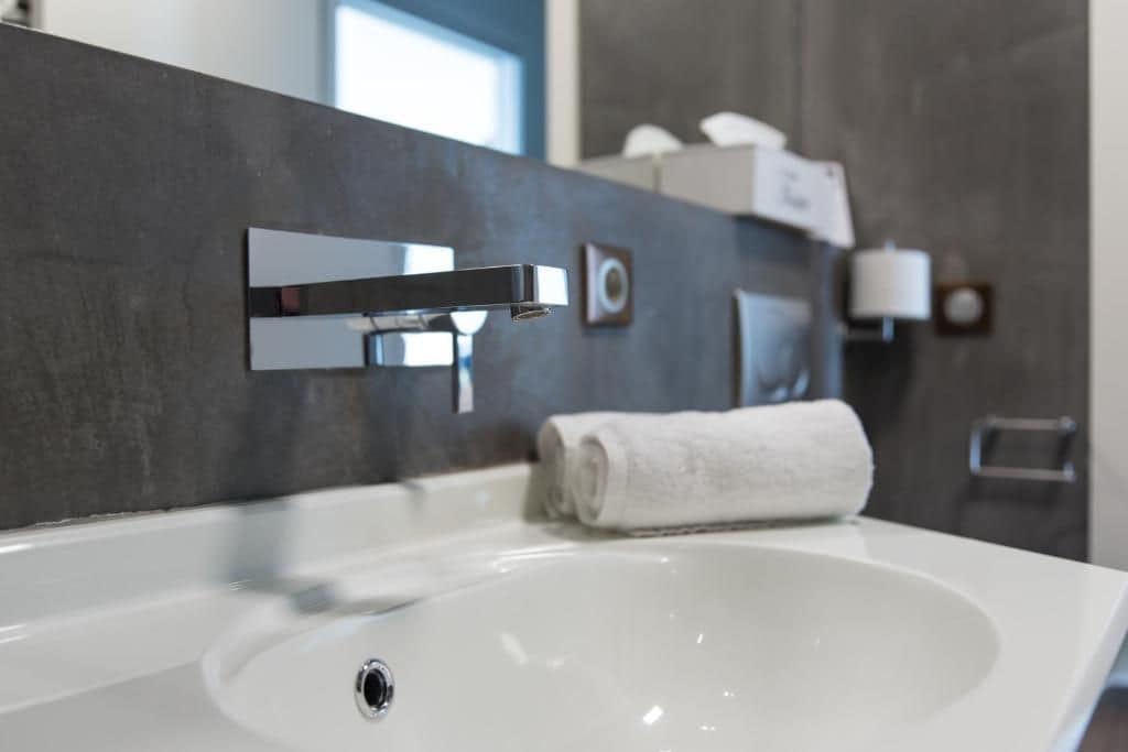 Een moderne badkamer met een witte wastafel, een chromen kraan en een handdoek op het aanrecht.