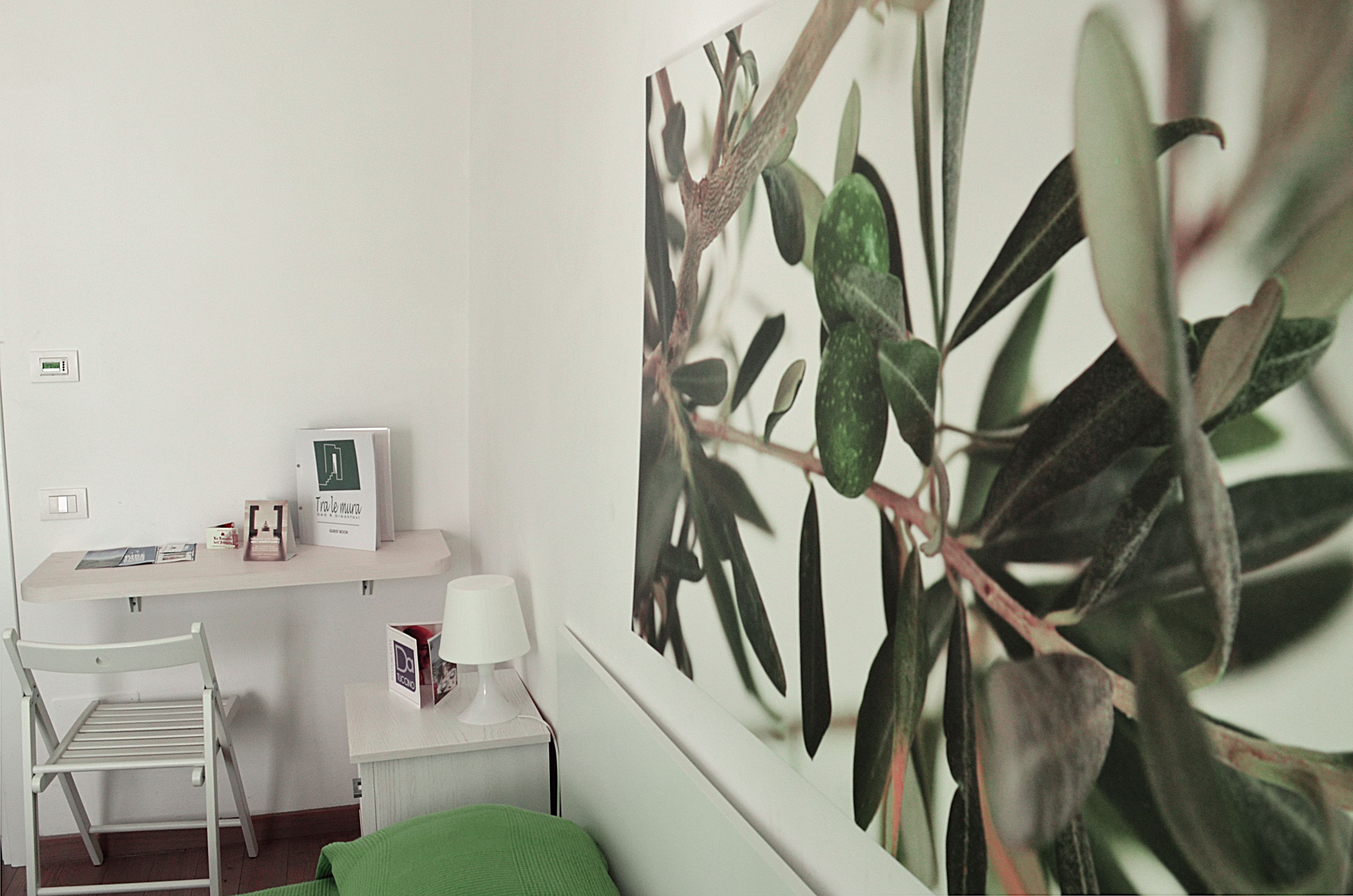 A room with a desk, a chair, a lamp, and a large plant.