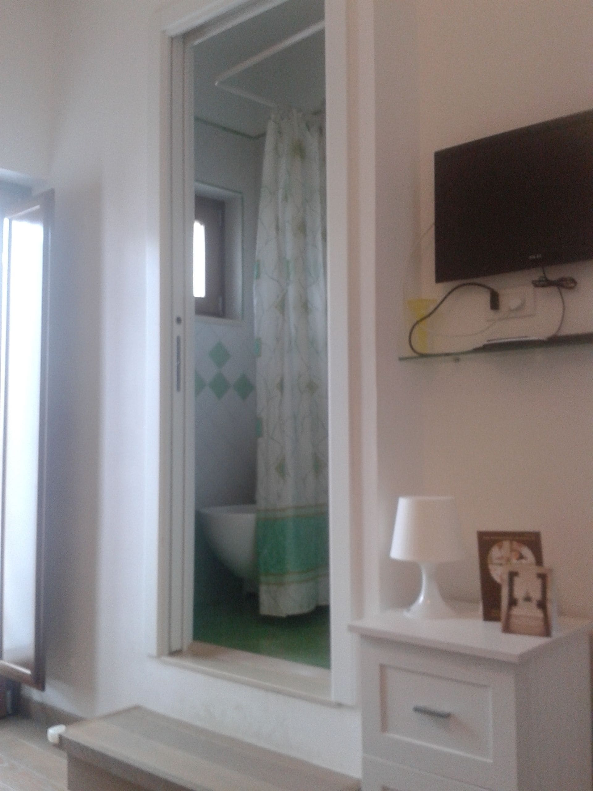 A bathroom with a shower, a toilet, and a sink. There is a television mounted on the wall above the sink.