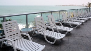 A row of white lounge chairs and a small table on a balcony overlooking the sea. - Apartmentos Playa Palmetto (Cartagena)