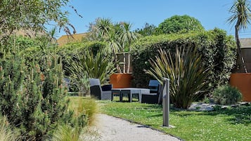 A garden with a pathway leading to outdoor furniture.