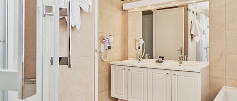 Un baño moderno con cabina de ducha de vidrio, un espejo grande y un mueble de tocador doble.