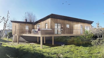 Een moderne, twee verdiepingen tellende aanbouw met een houten gevel, een balkon en een gazon.