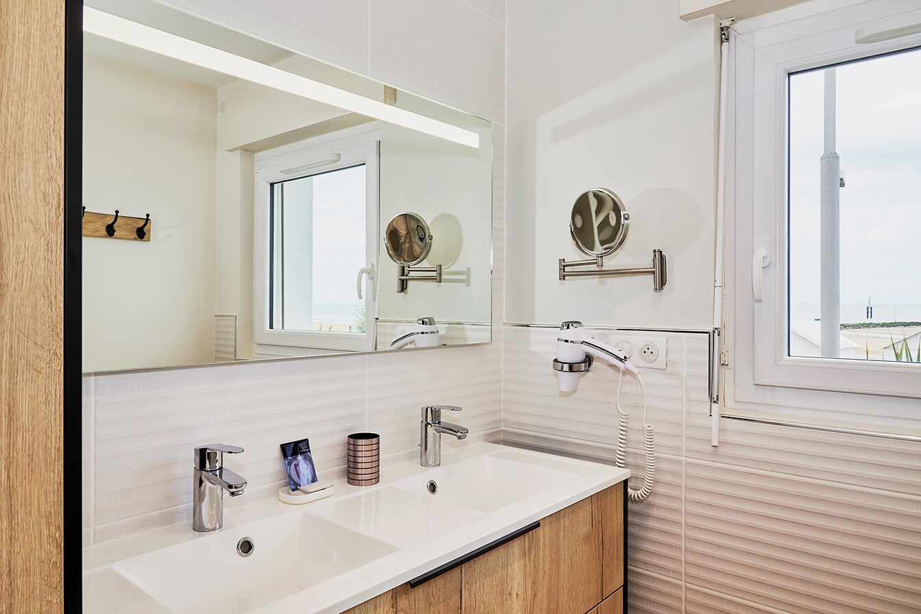 Ein modernes Badezimmer mit einem großen Spiegel, zwei Waschbecken, einem Waschtisch und einem Fenster mit Blick.