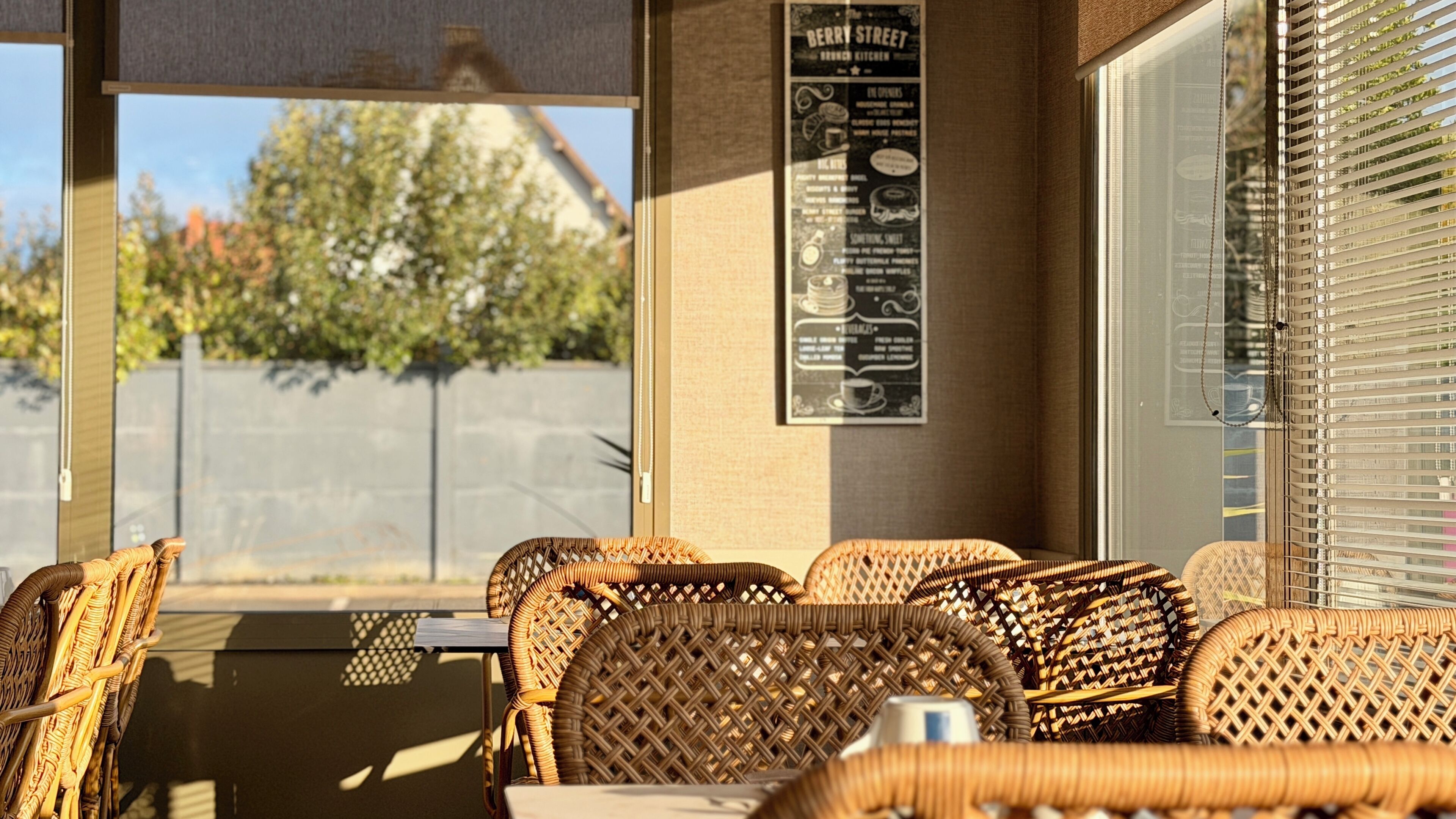 A covered outdoor seating area with wicker furniture and a menu board on the wall.