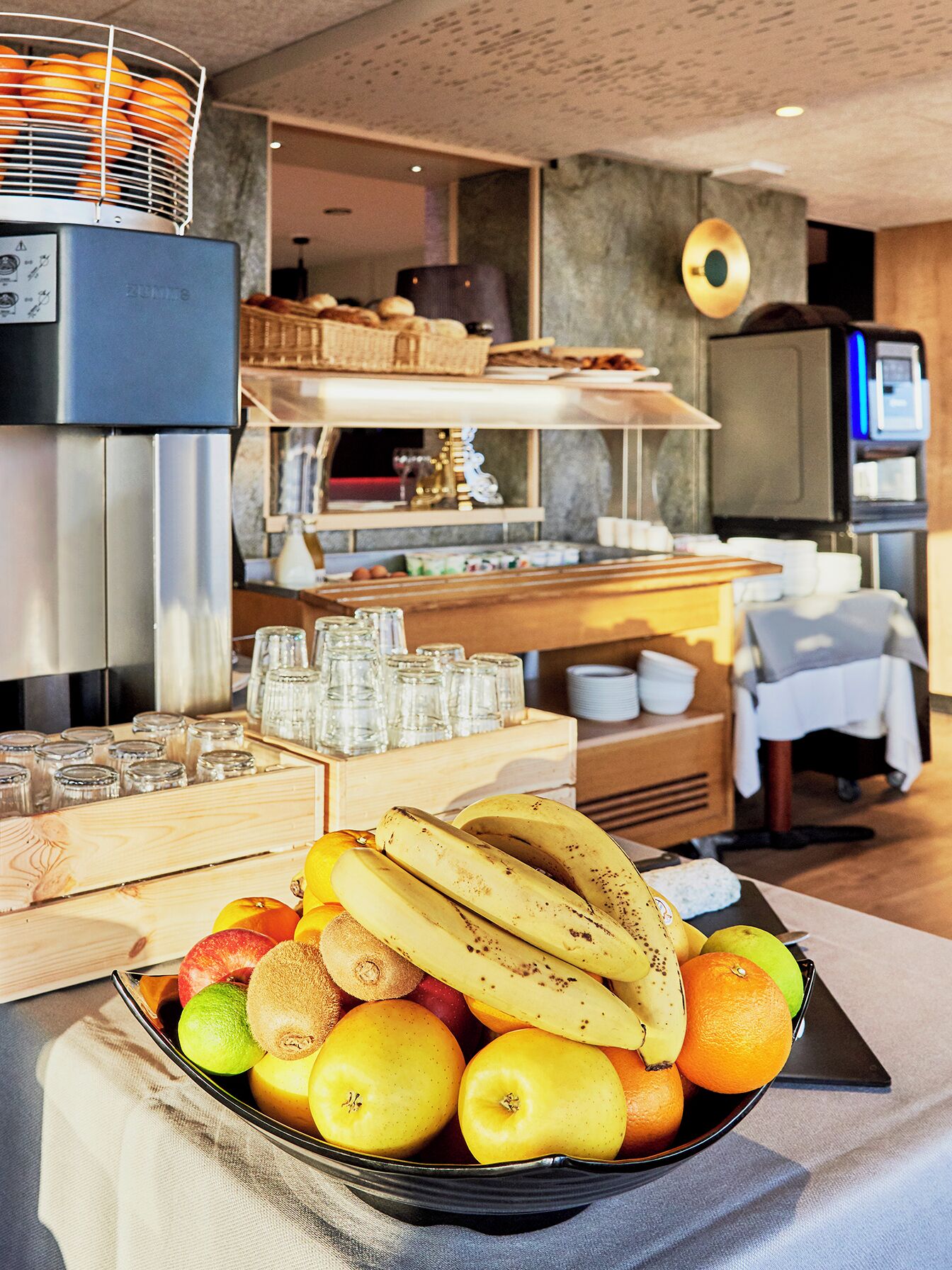 Un bufé de desayuno con diversas frutas y una cafetera.