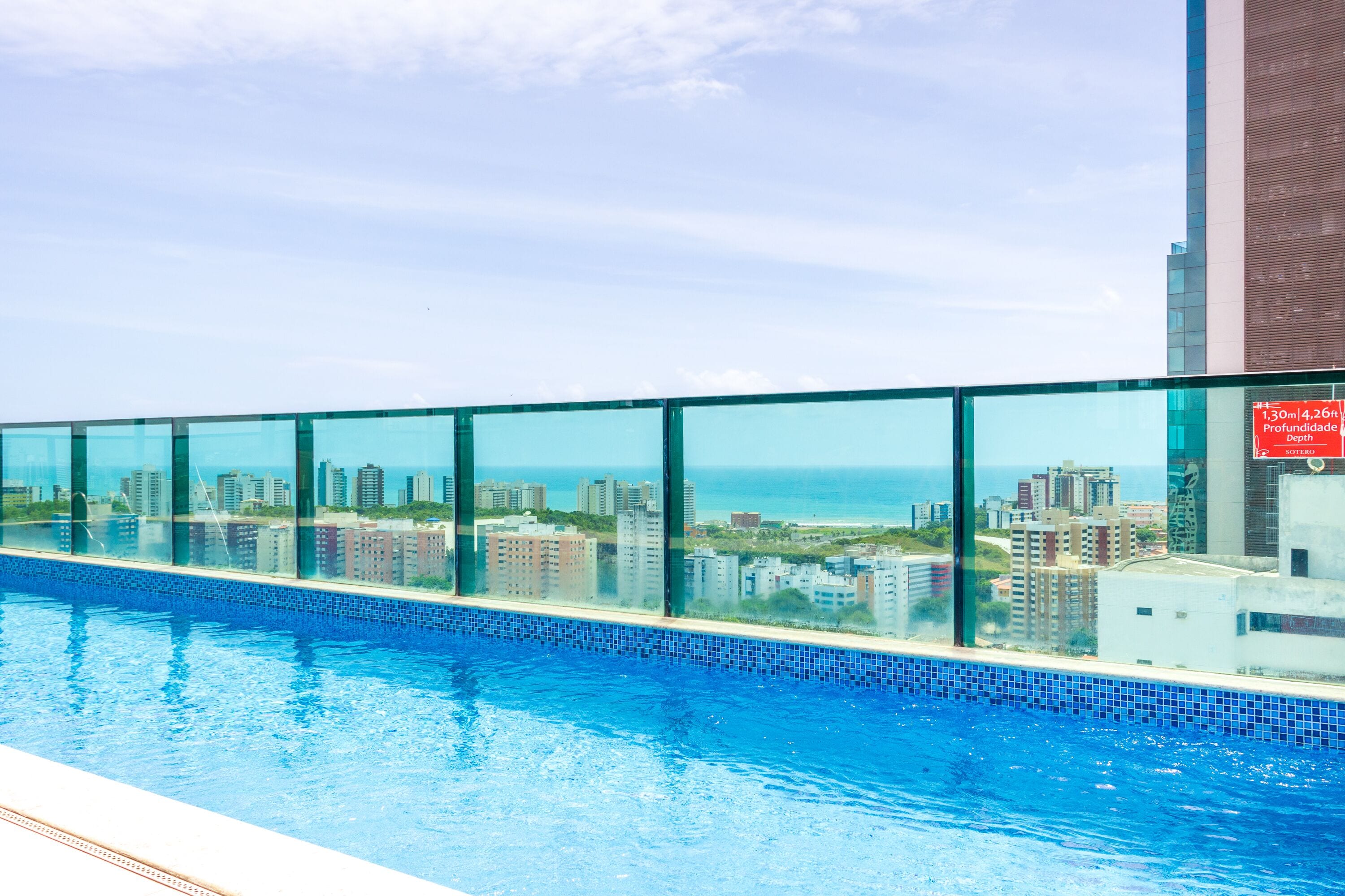 A swimming pool with a city view, surrounded by glass panels.