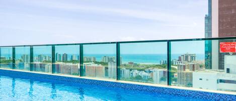 A swimming pool with a city view, surrounded by glass panels.