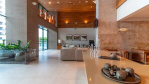 A spacious lobby with a long reception desk, comfortable seating, and a modern design featuring brick walls and wooden ceilings. - Sotero Hotel (Salvador)
