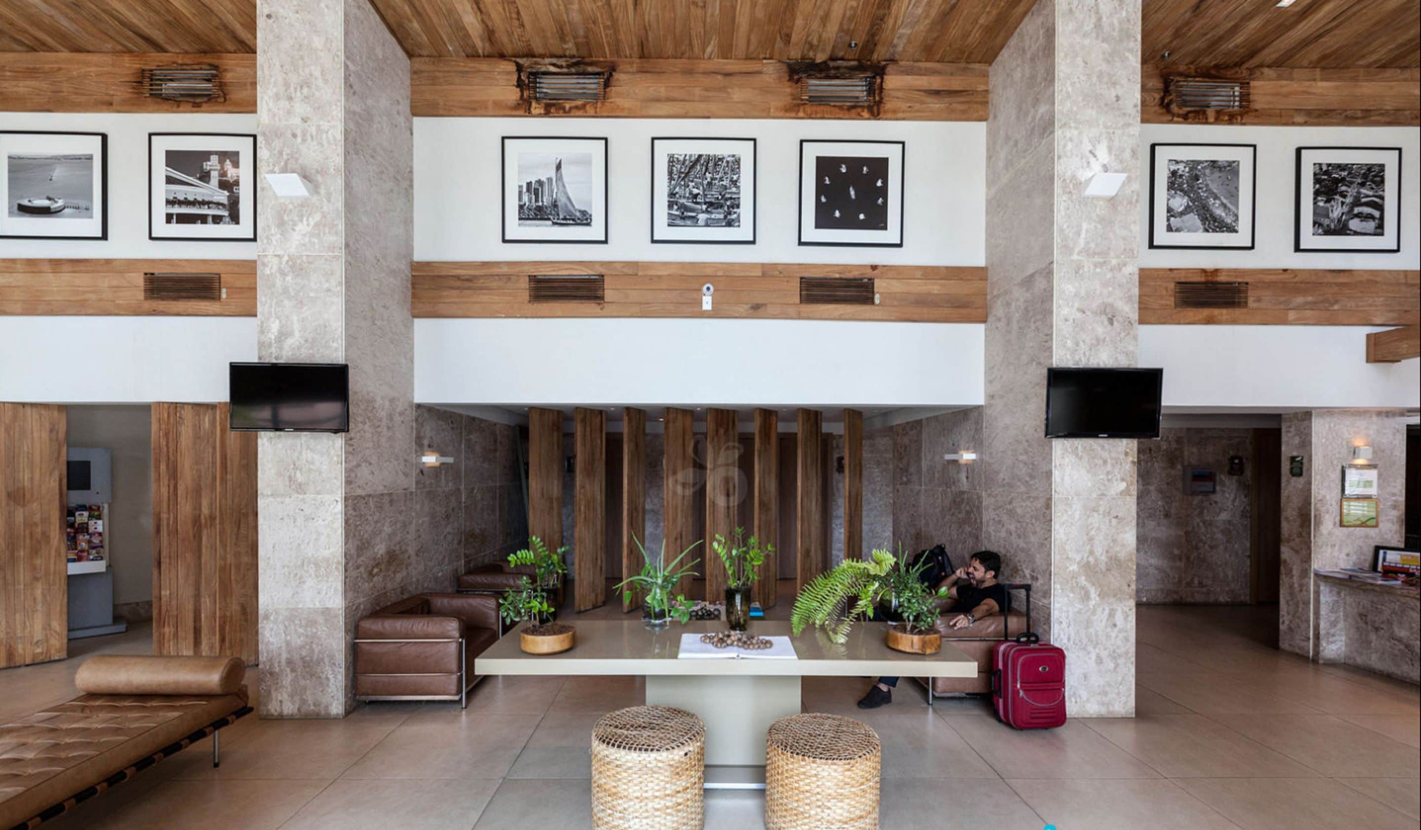 A spacious lobby with a central seating area, wooden beams on the ceiling, and framed pictures on the walls.