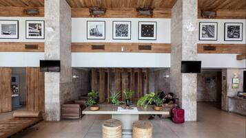 A spacious lobby with a central seating area, wooden beams on the ceiling, and framed pictures on the walls.