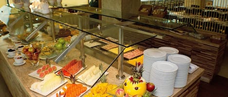 A buffet with various fruits, vegetables, and a decorative pineapple centerpiece.