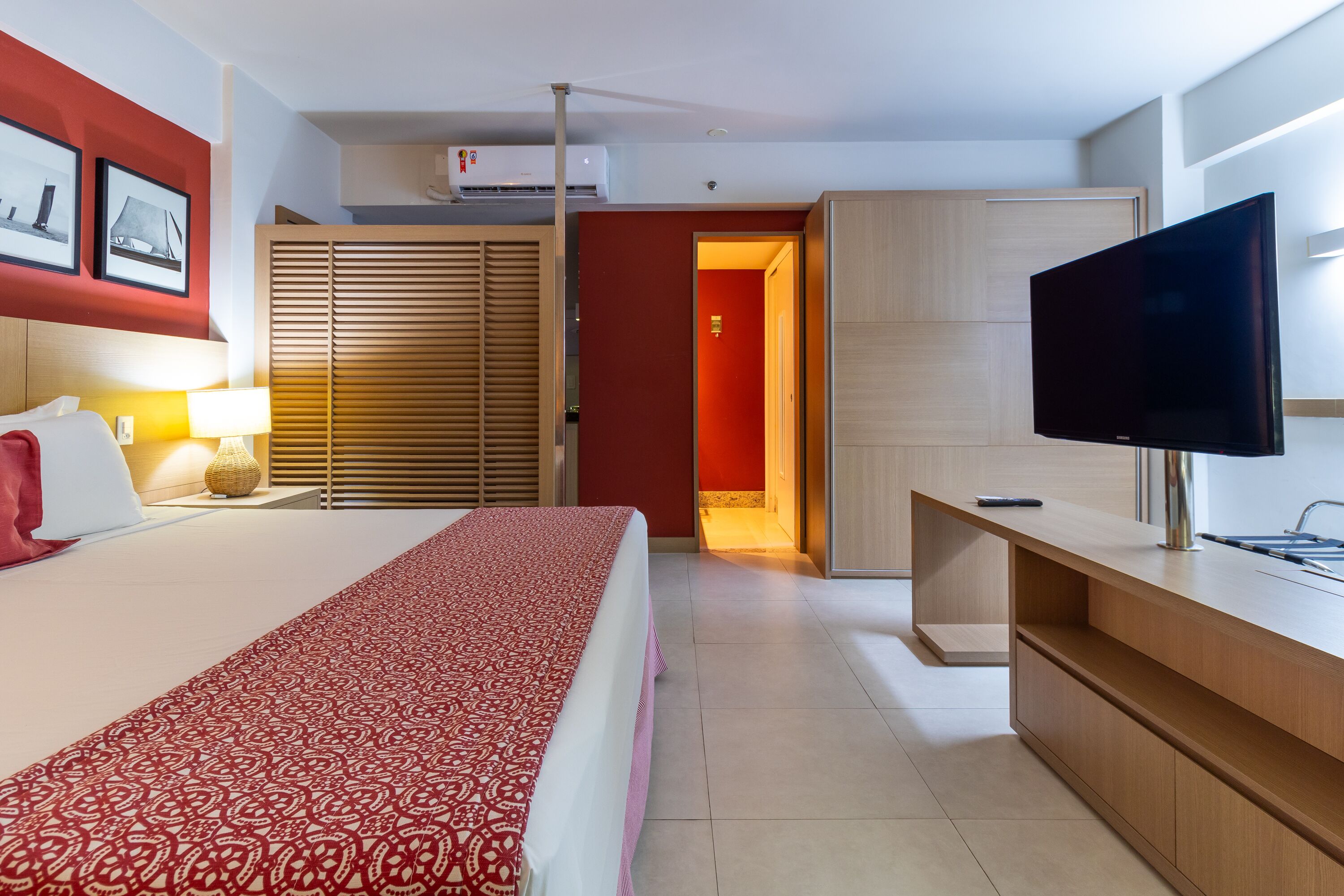 A hotel room with a bed, a TV, a desk, and a wardrobe.