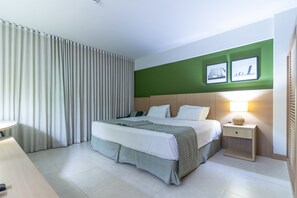 Ein modernes Hotelzimmer mit einem großen Bett, einem Nachttisch mit Lampe und einer grünen Akzentwand.