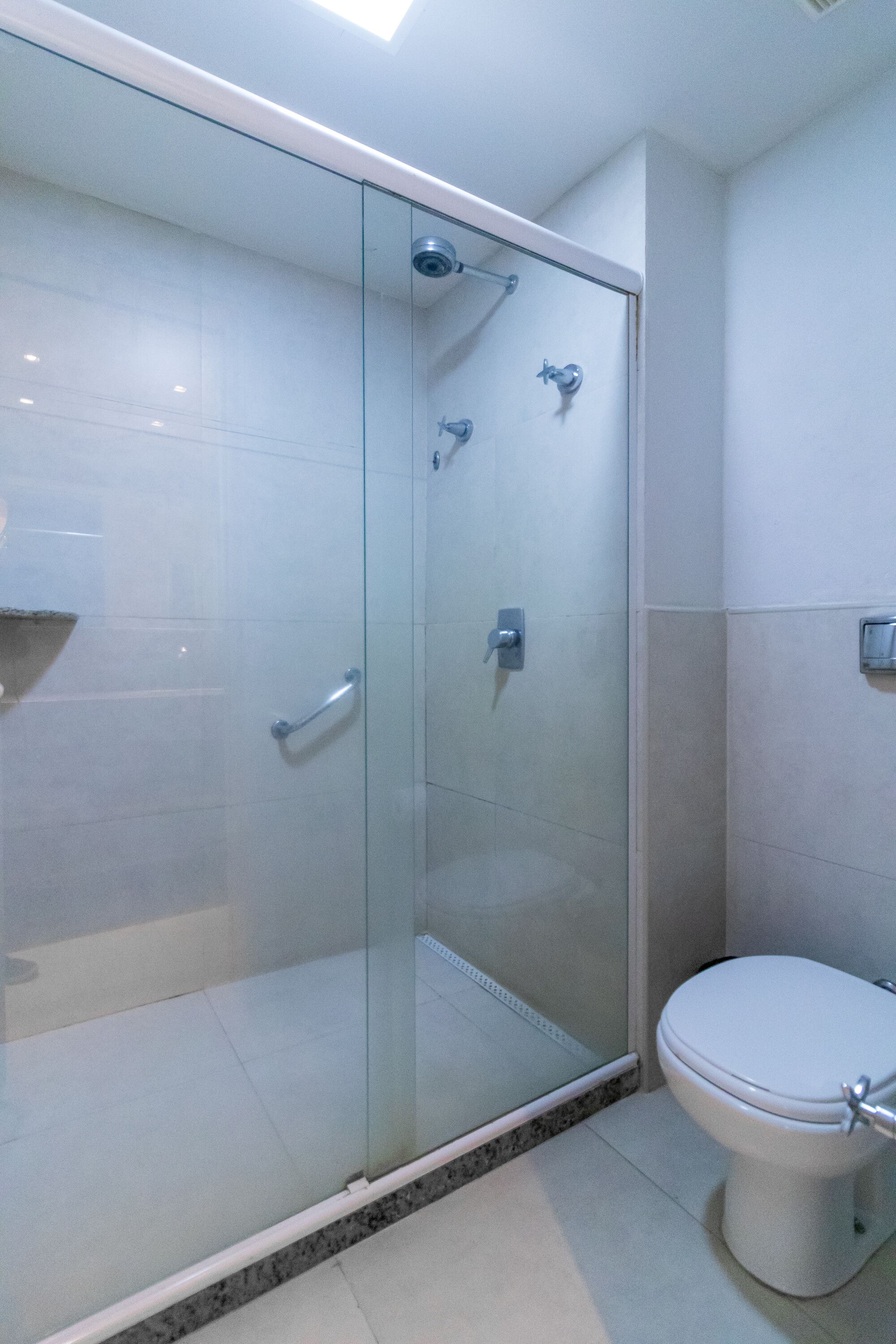 Ein modernes Badezimmer mit einer Glasdusche, einer Toilette und einem Fliesenboden.