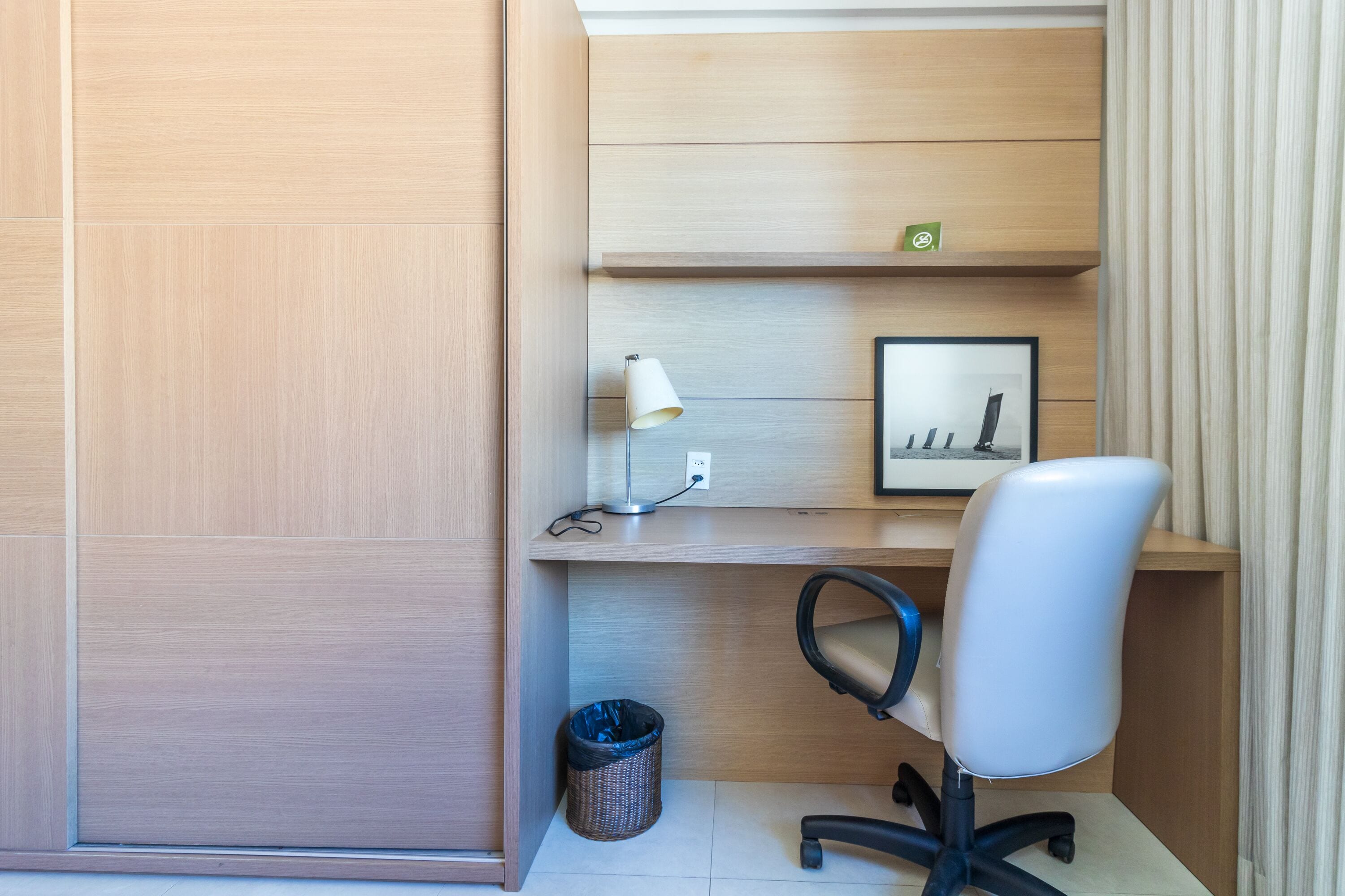 Un espacio de oficina moderno con un escritorio, una silla, una lámpara y un cuadro en la pared.