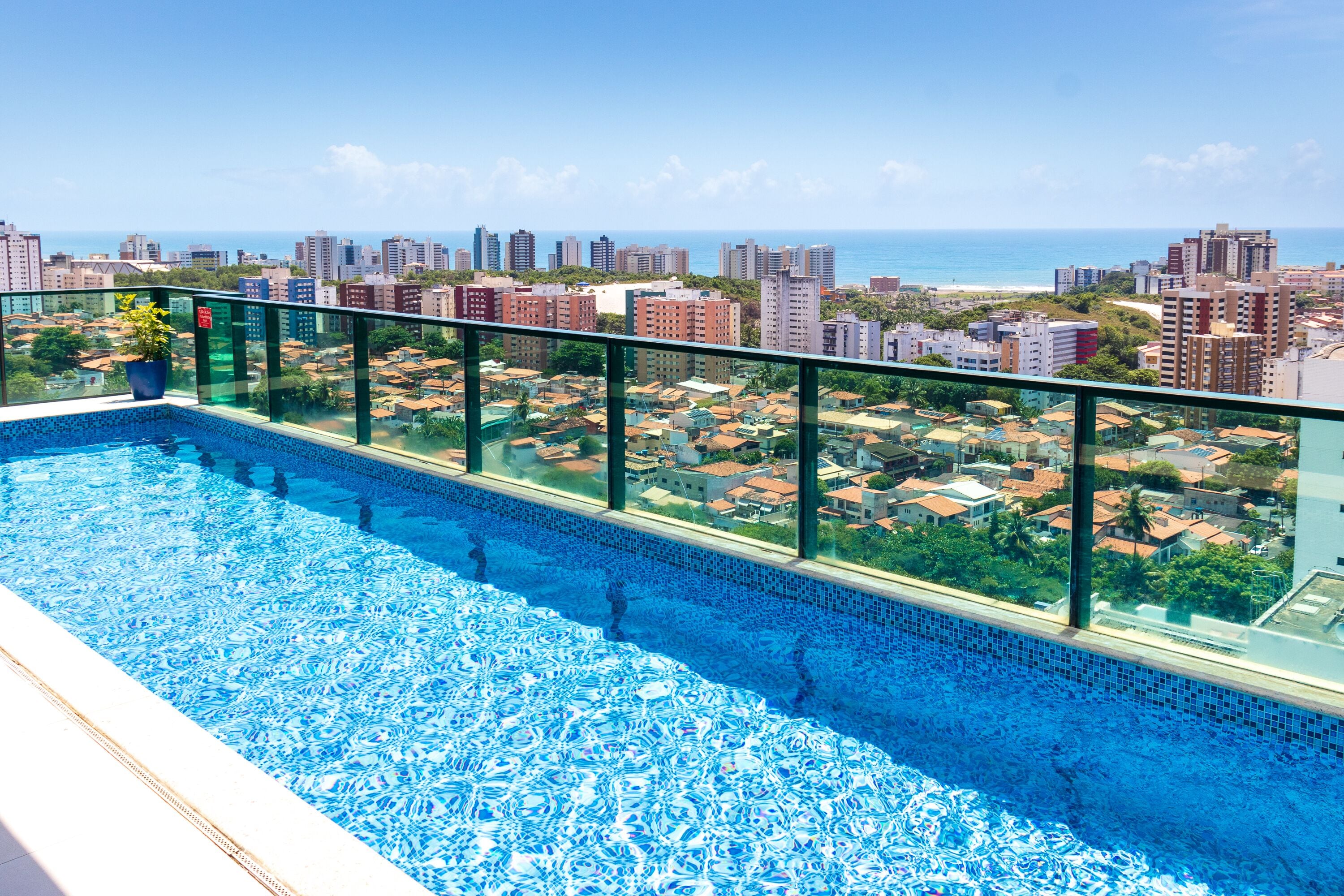 A rooftop pool with a city view, surrounded by high-rise buildings and a clear sky.