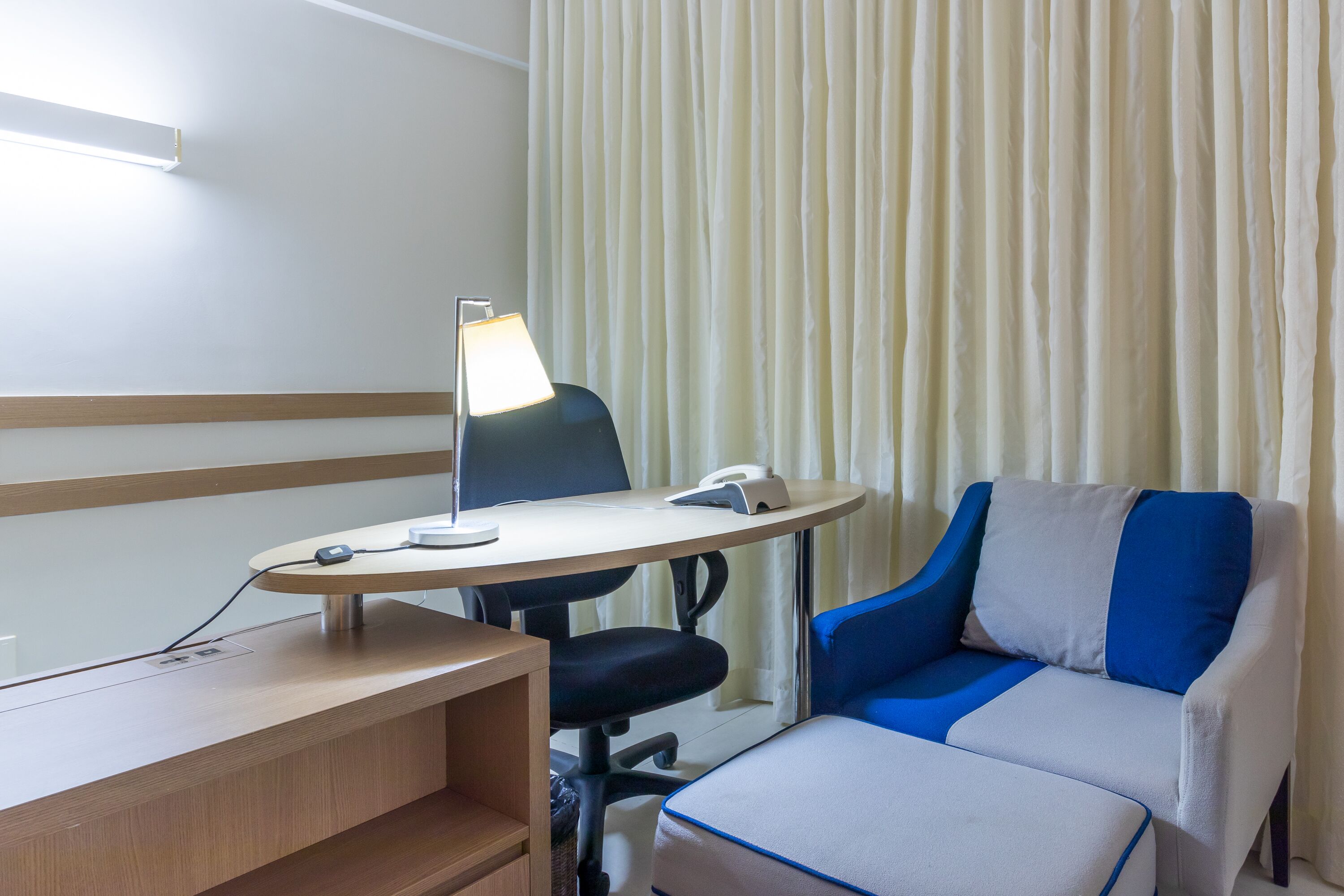 A hotel room with a desk, chair, and a sofa.