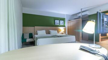Ein Hotelzimmer mit Bett, Schreibtisch, Lampe, Fernseher und Kleiderschrank.