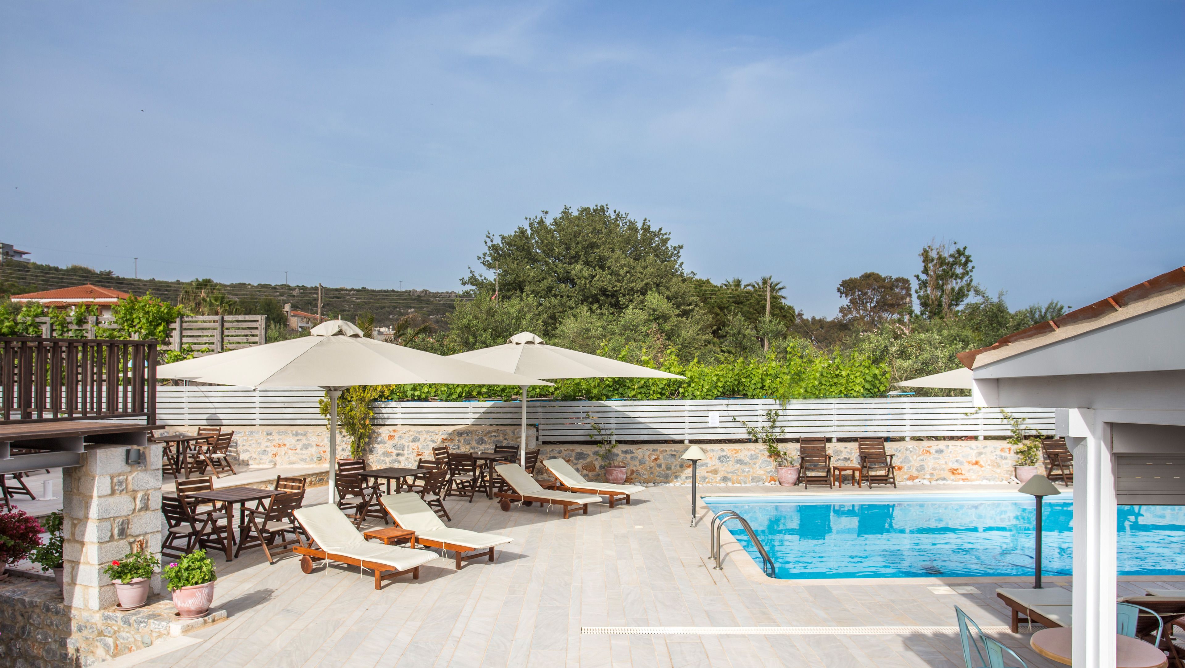 A poolside area with lounge chairs, umbrellas, and a pool.